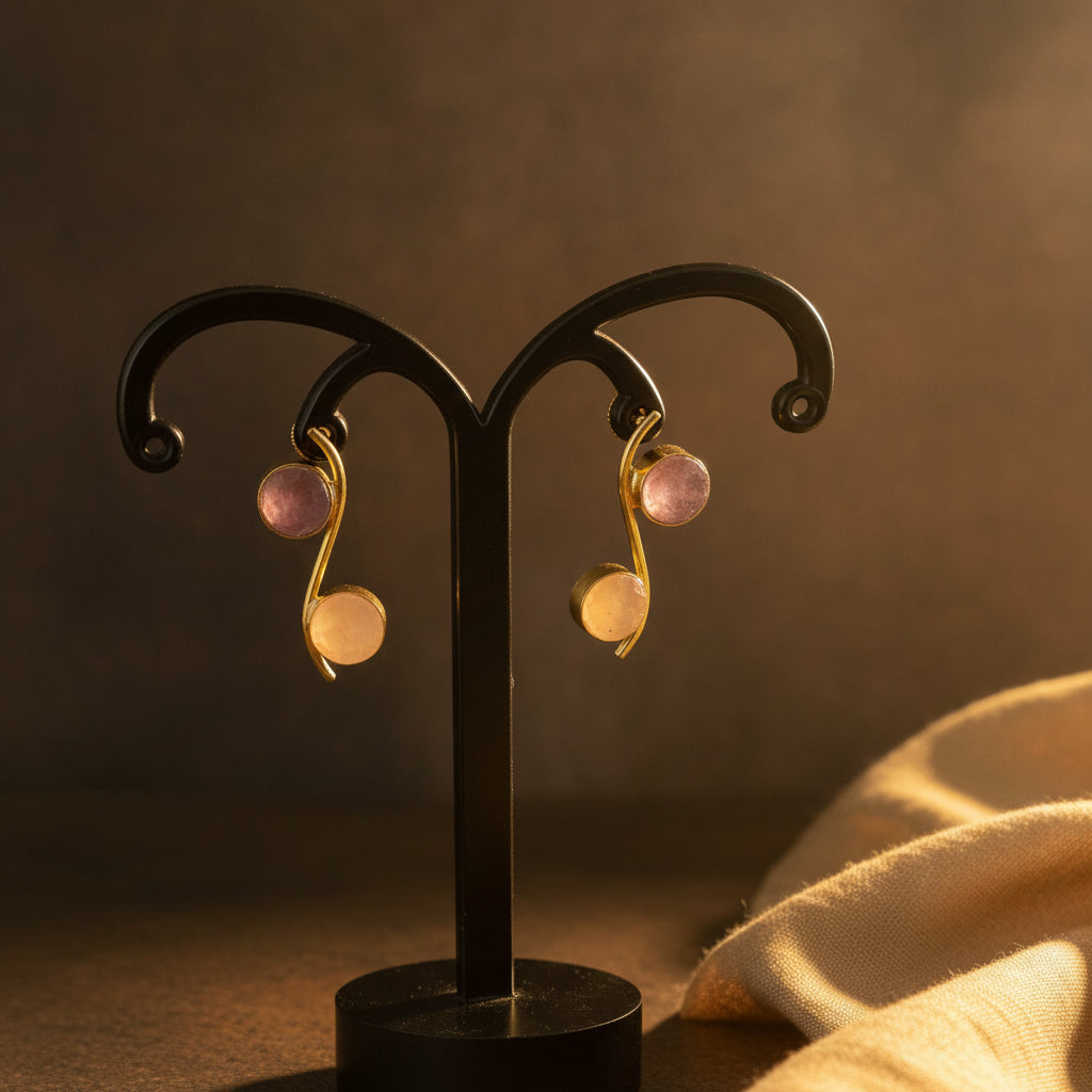 A pair of gold-tone earrings with round lavender purple gemstones, displayed on a black metal music note stand against a black velvet background.