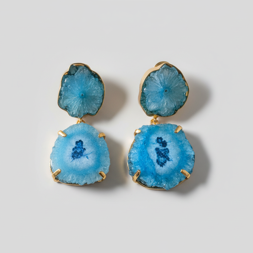 Blue geode-style earrings on a striped fabric background