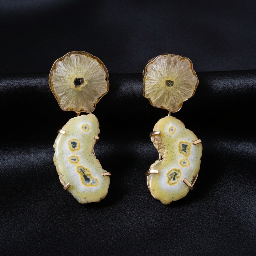 Pair of earrings with a textured design on a blue and green striped fabric background