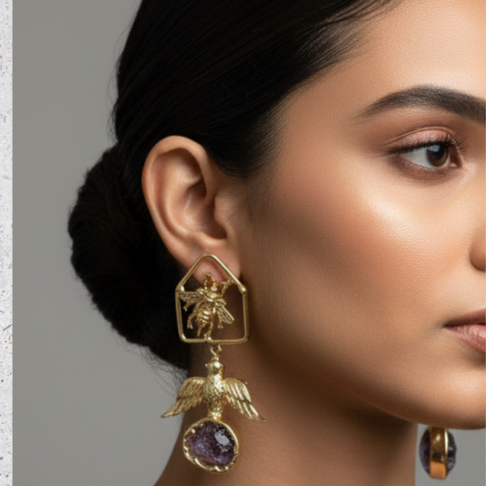 Close-up of a woman wearing gold earrings with a bee design on a neutral background