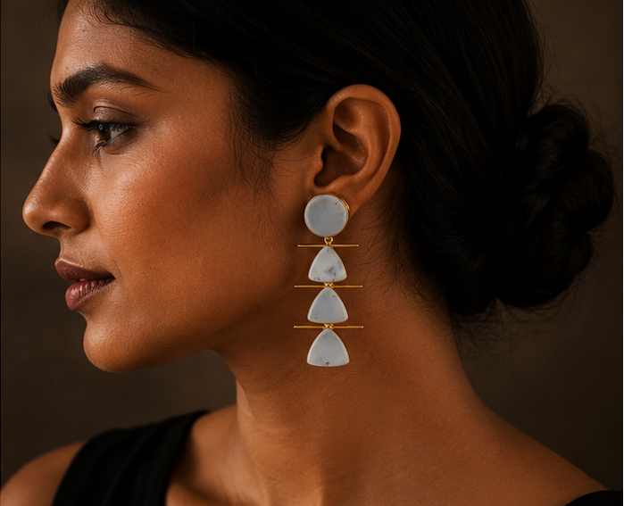 Three-panel product photo of statement dangle earrings. The left panel shows the earrings hanging on a gold display stand against a dark brown background.