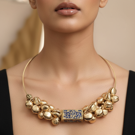 Woman wearing a gold necklace with a prominent clasp against a neutral background