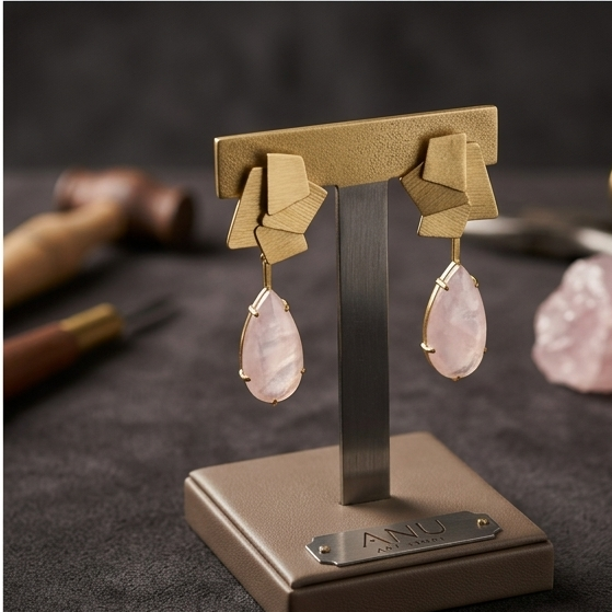 geometric drop earrings with pink teardrop stones on a display stand, a close-up of the earrings laid out, and a woman in a dark blazer wearing the earrings.