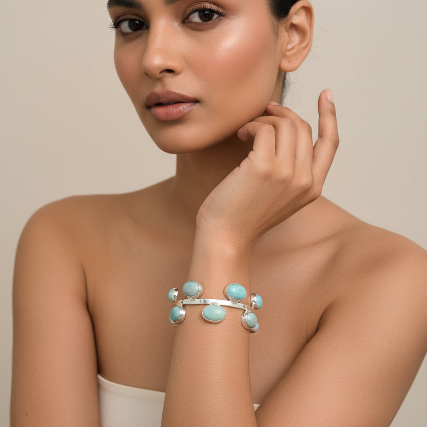 Silver bracelet with turquoise stones on a wrist against a blurred background