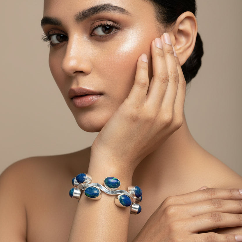 Hand wearing a silver bracelet with blue stones on a tiled floor background