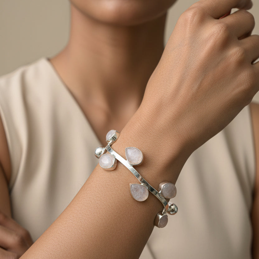 Silver bracelet with clear stones on a wrist against a dark background
