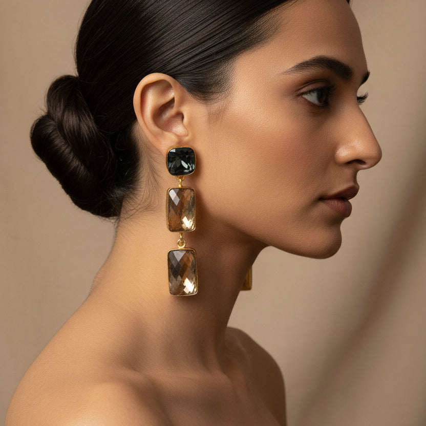 Pair of gold and smoky quartz earrings on a green fabric background