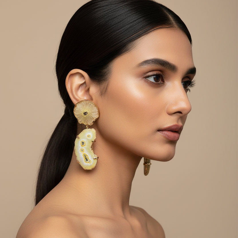 Pair of earrings on a textured blue and green fabric background