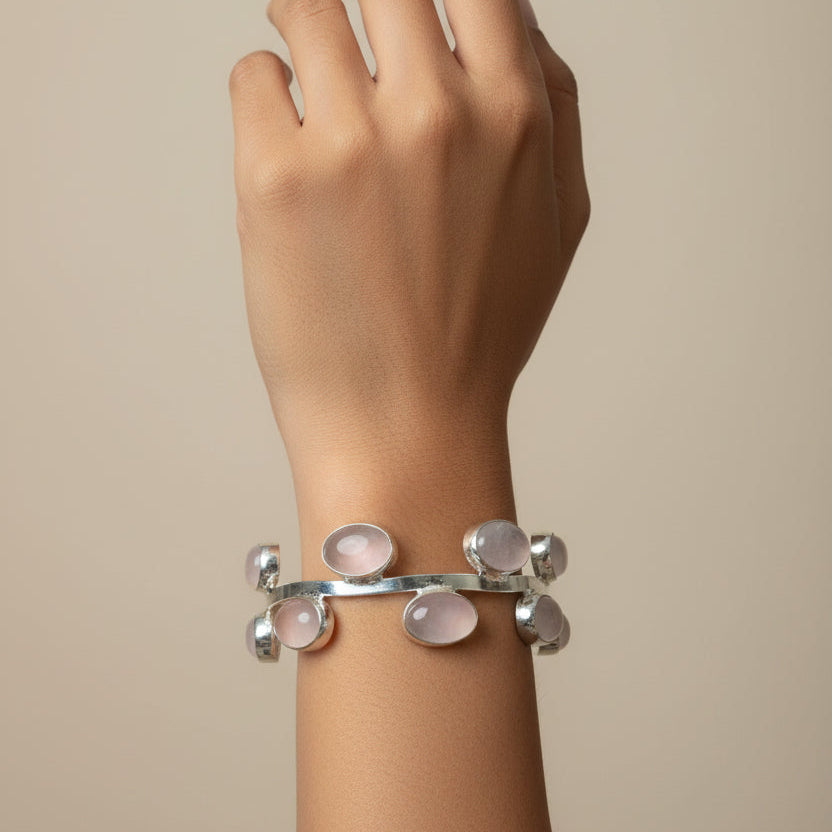 Silver bracelet with pink stones on a wrist, blurred background