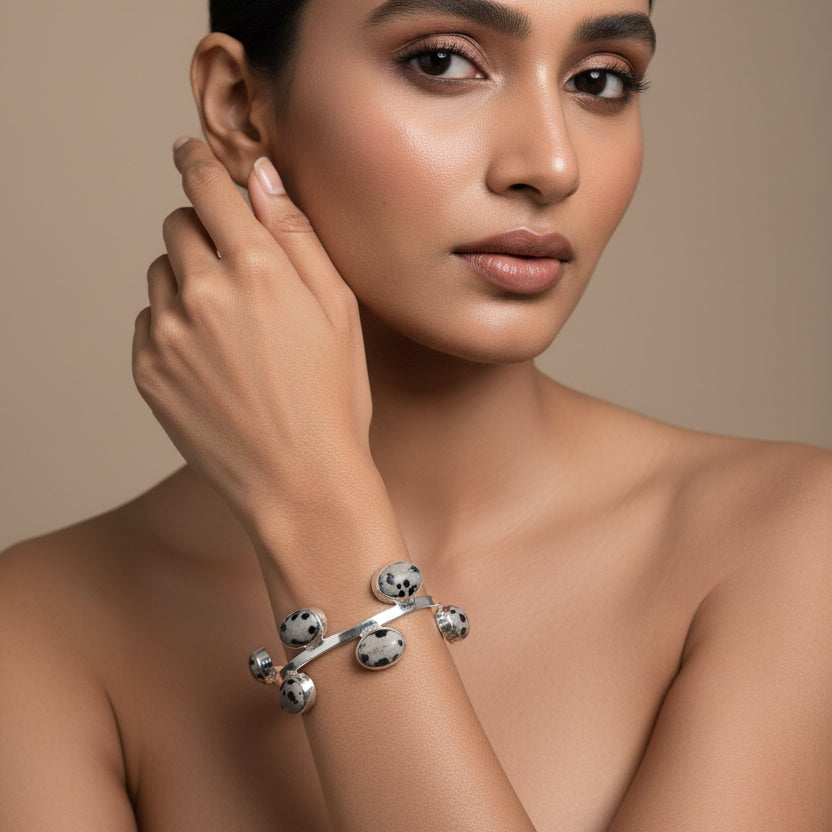 Silver bracelet with circular charms on a wrist against a blurred background