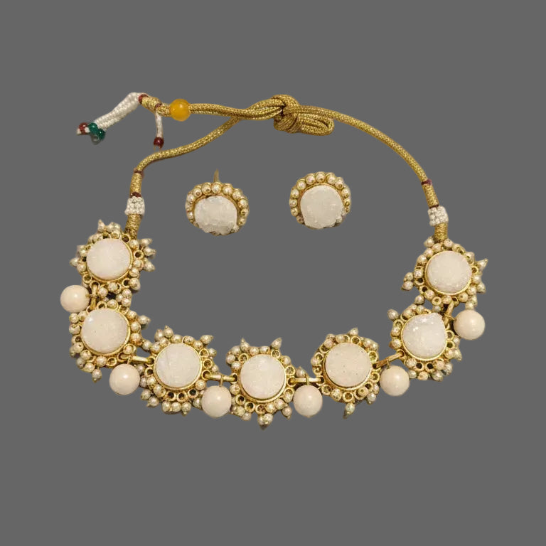 Gold and white jewelry set on a dark fabric background