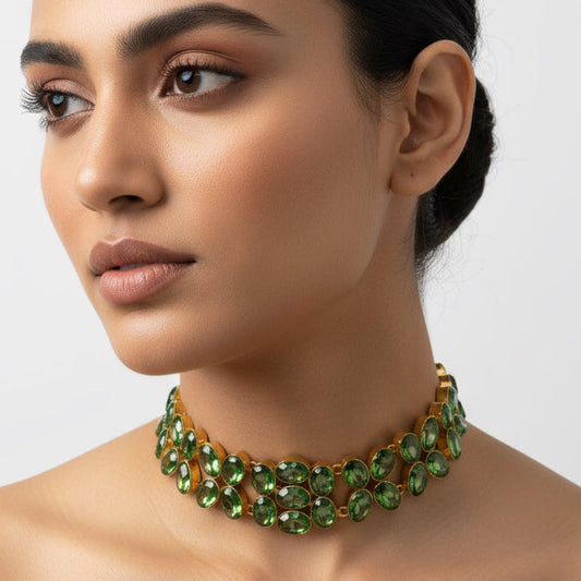 Woman wearing a green gemstone necklace on a plain background